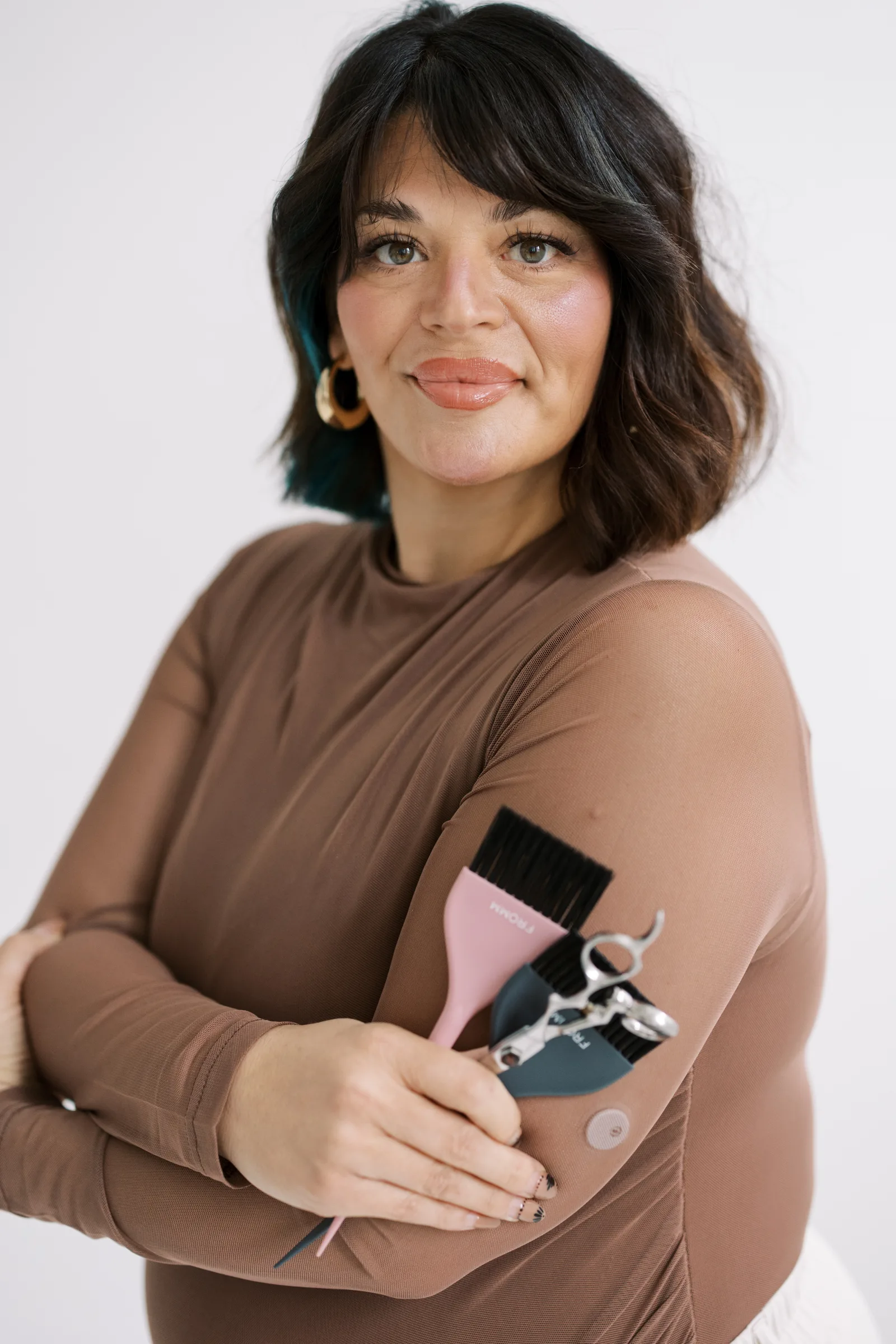 A Salon Joy stylist smiling, holding her styling tools
